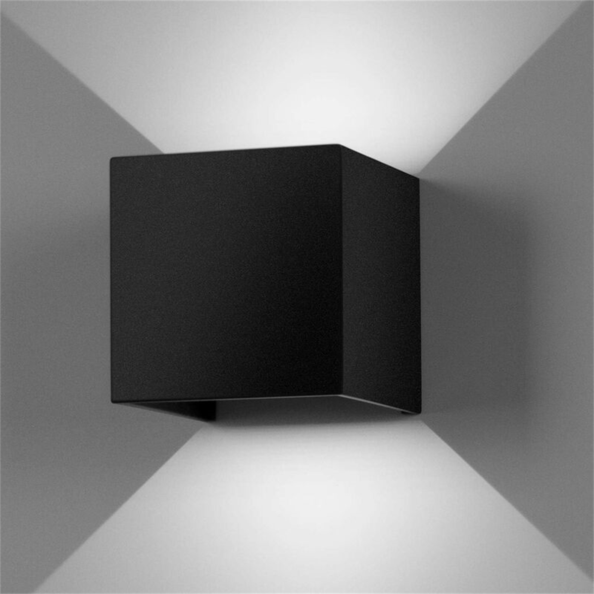 Eine schwarze quadratische Wandleuchte, die Licht in zwei Richtungen abstrahlt. Die Wand ist grau.
