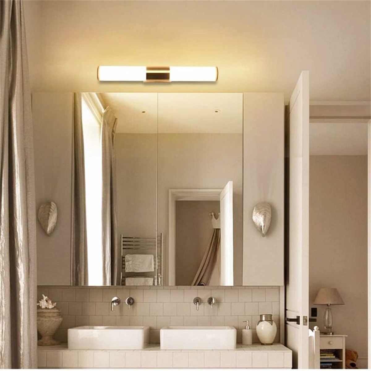 Badezimmer mit großem Spiegel, zwei Waschbecken, einer Leuchte und einer teilweise geöffneten Tür.