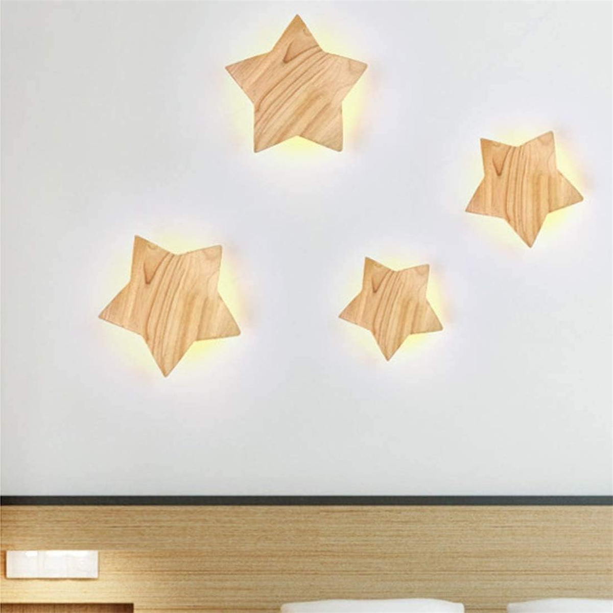 Vier hölzerne sternförmige Lichter an einer weißen Wand. Die Lichter leuchten. Ein Kopfteil ist darunter.