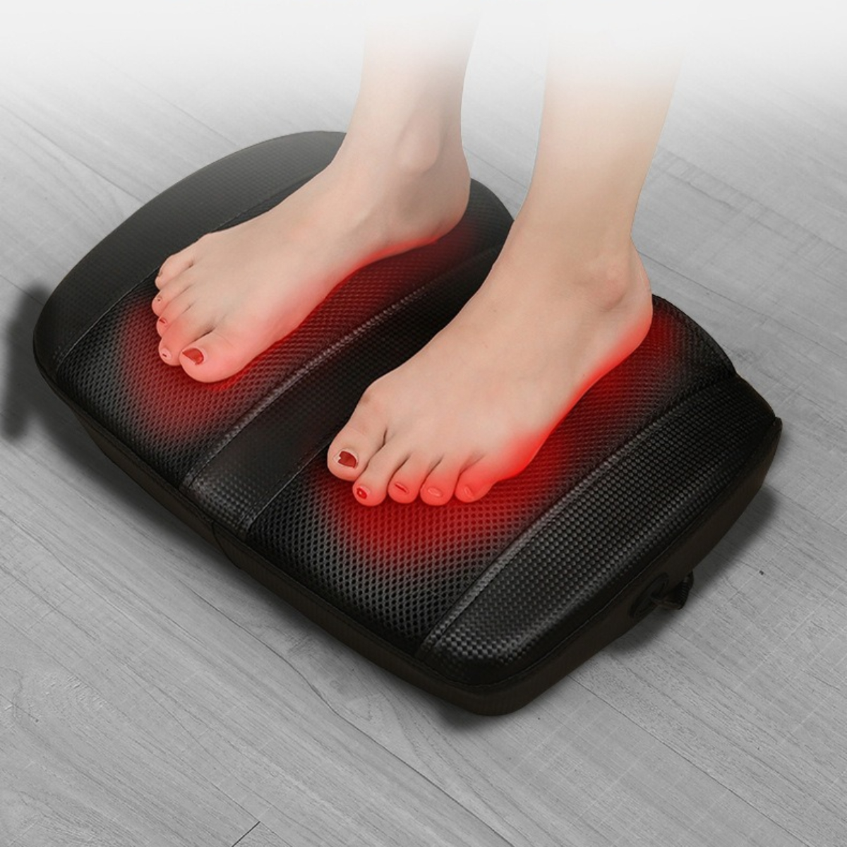 Füße auf einem schwarzen Massagepad mit rotem Glühen an den Füßen.