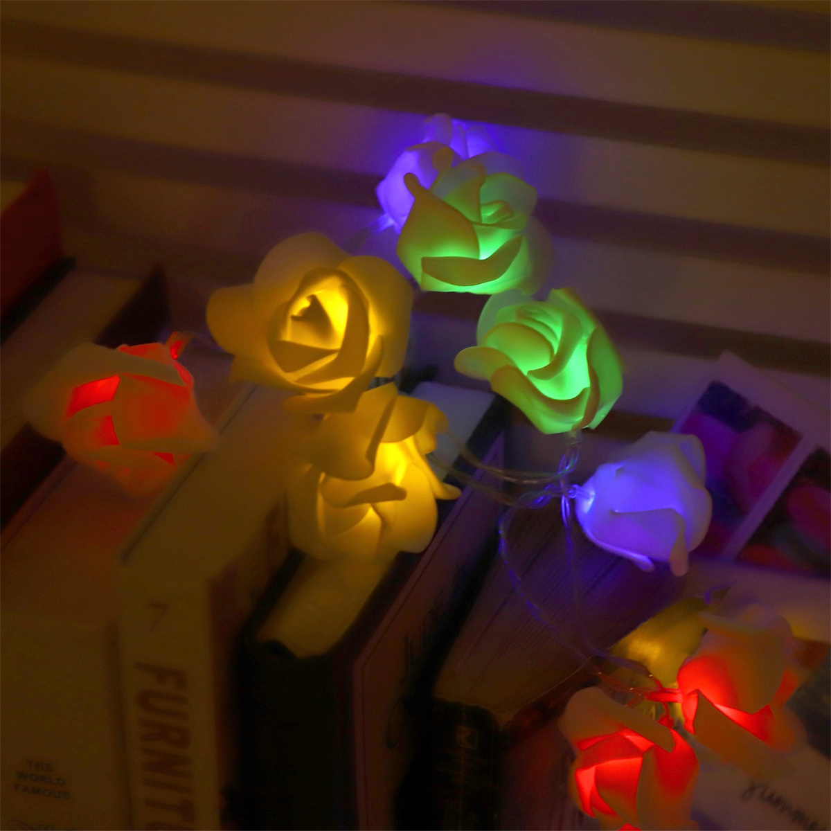 Beleuchtete Rosenblütenlichter auf Büchern, farbenfrohe, beleuchtete Darstellung, dunkler Hintergrund.