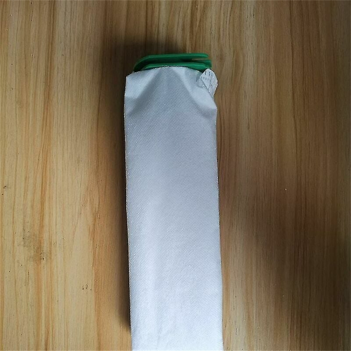 Ein weißes Filterelement mit grünem Deckel liegt auf einer Holzoberfläche.