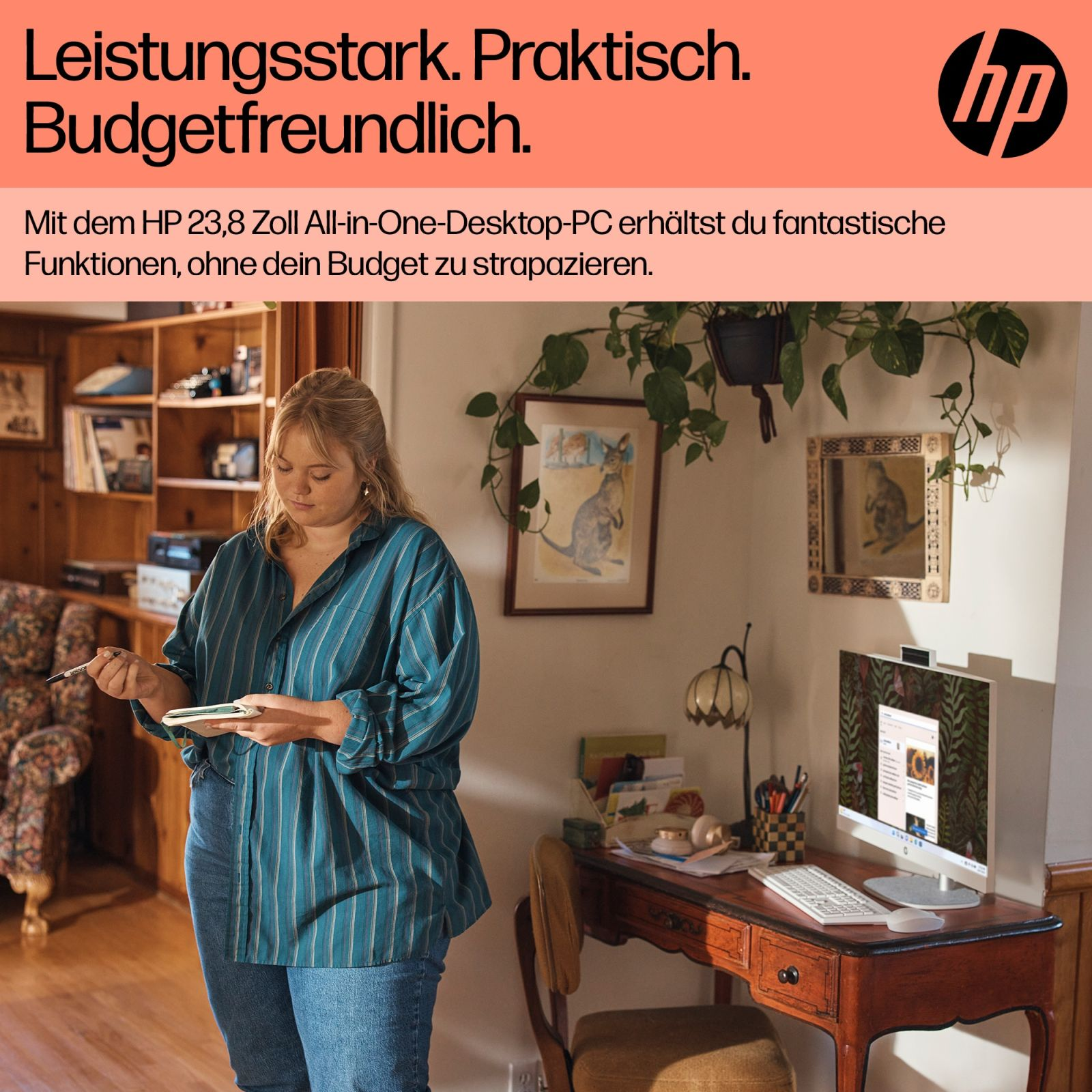 Kobieta w niebieskiej koszuli, stojąca przy biurku z komputerem. Regały i grafika ścienna w tle.