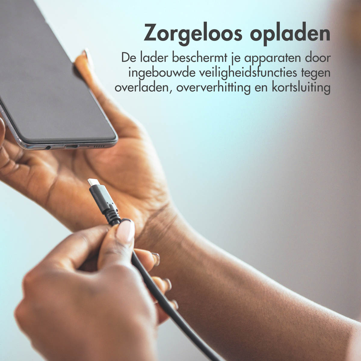 A person's hands holding a phone and plugging in a USB-C charger.
