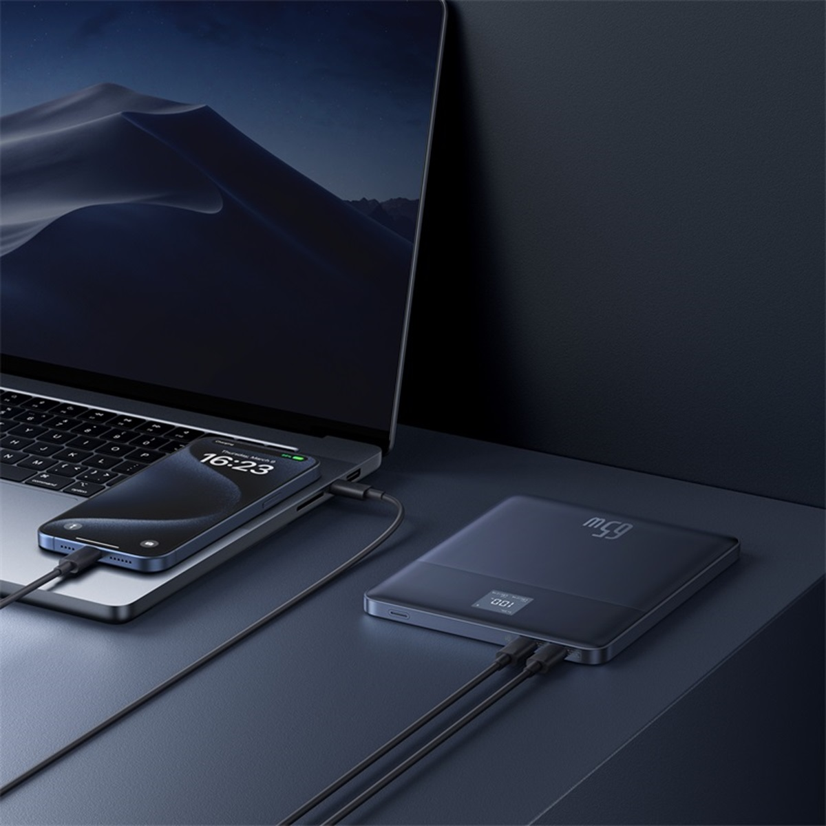 Portátil, teléfono y batería externa conectados. Teléfono muestra 16:23. Batería externa muestra 100%.
