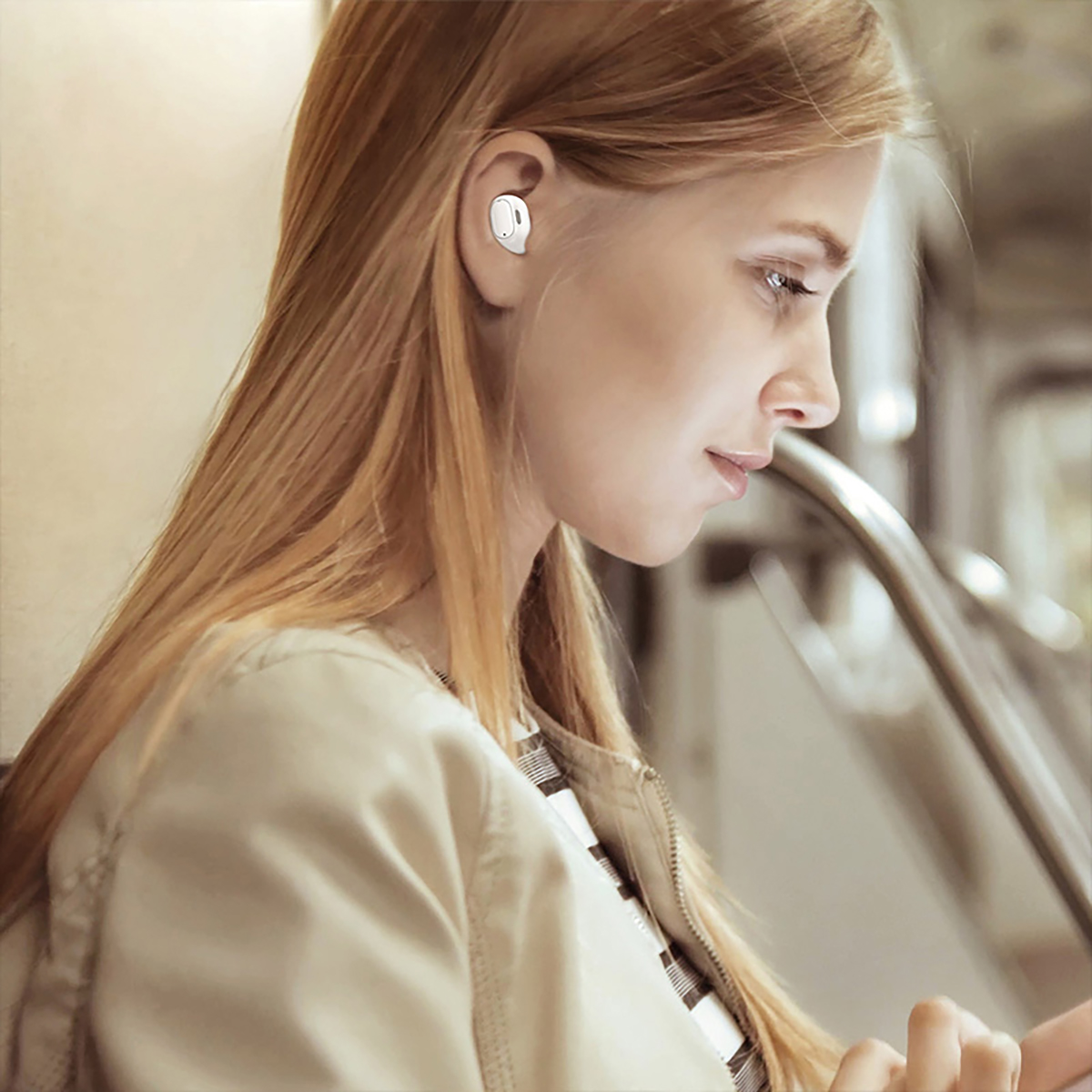 Donna con capelli biondi con auricolari nell'orecchio. È su un treno.