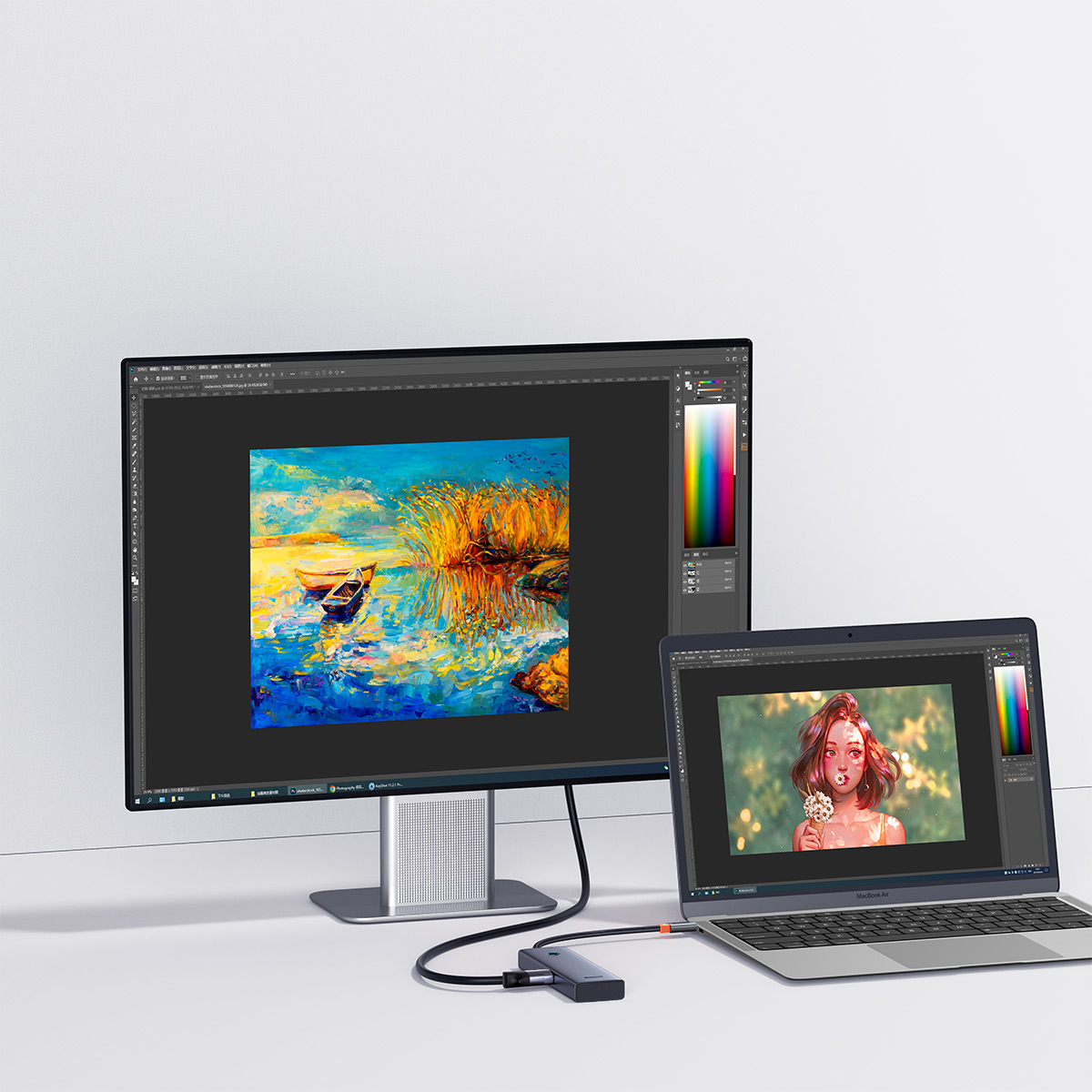 Een computermonitor en een laptop met kunstwerken, verbonden met een hub.