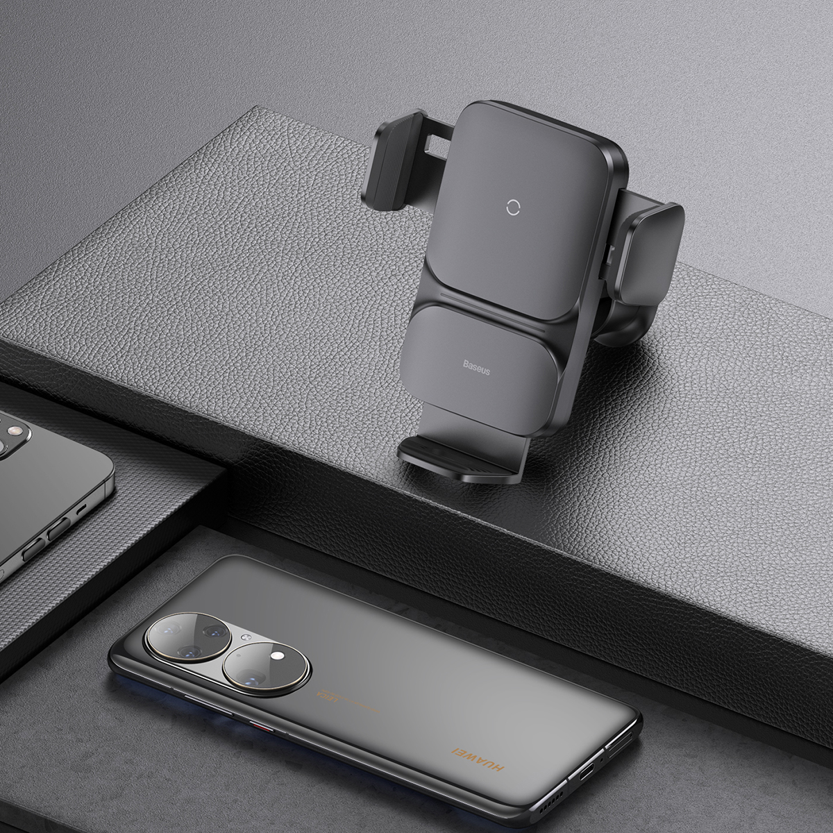 Black phone holder on a dark surface with a phone and a Huawei phone.