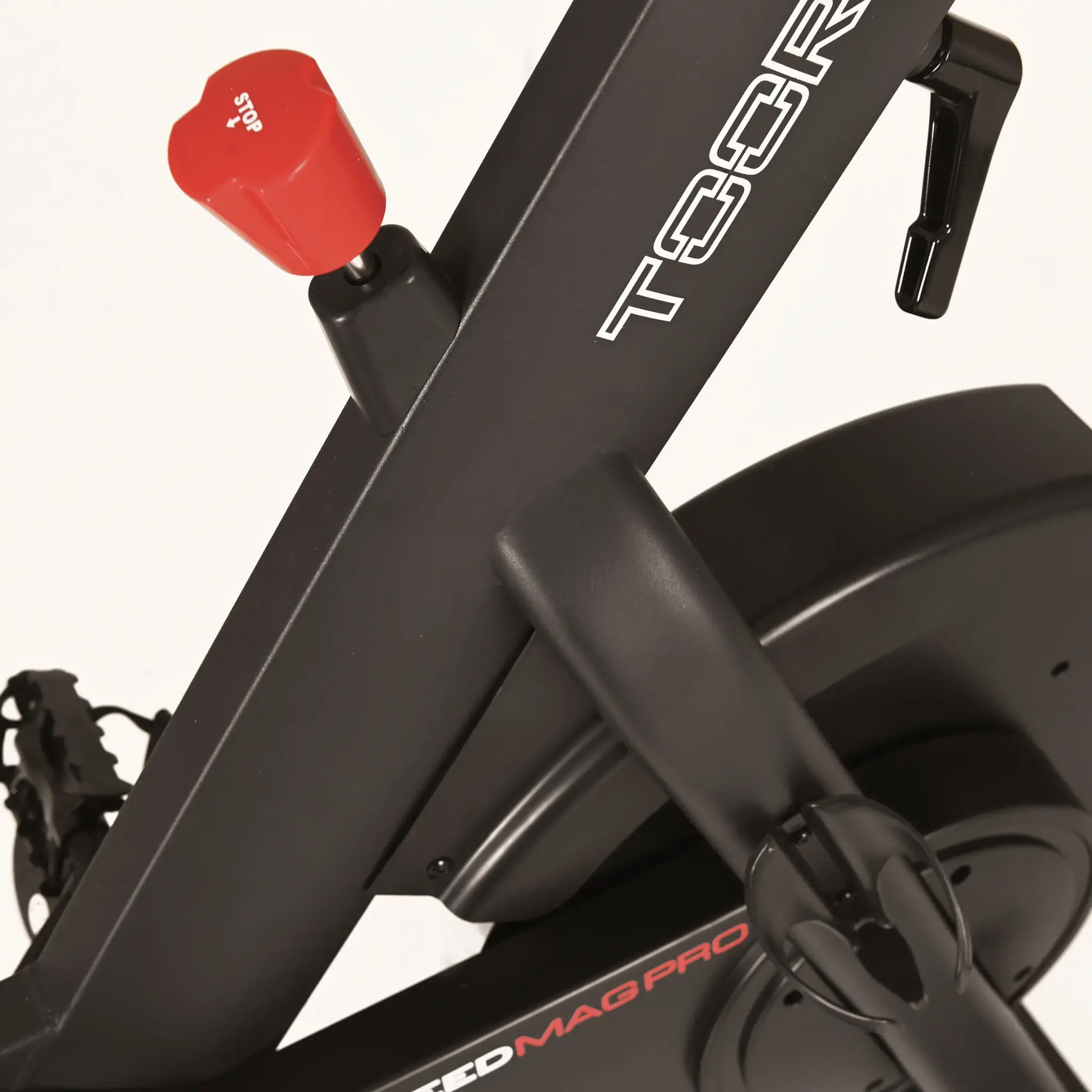 Close-up van een stationaire hometrainer, met de rode stopknop en branding.