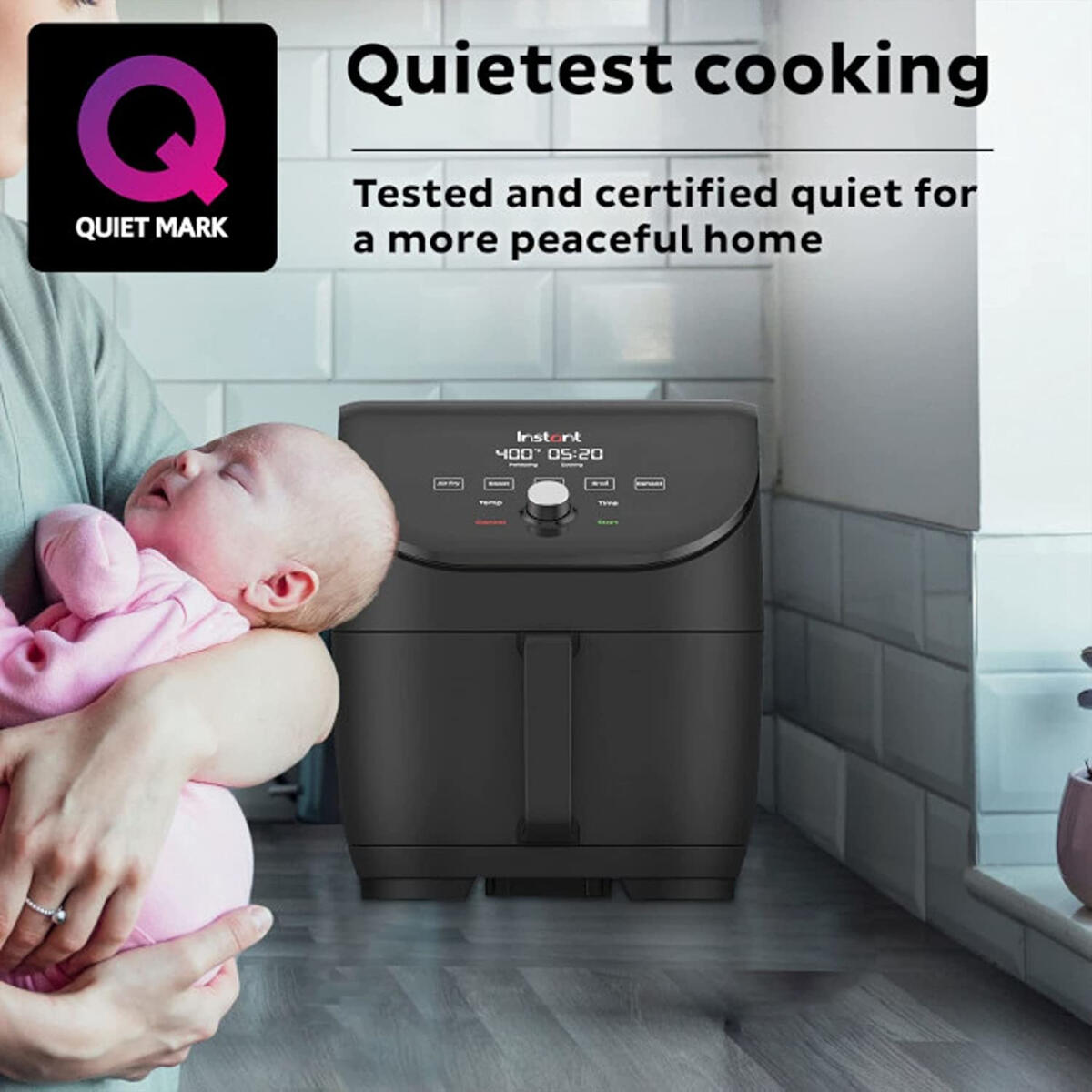Woman holding sleeping baby next to a black air fryer.