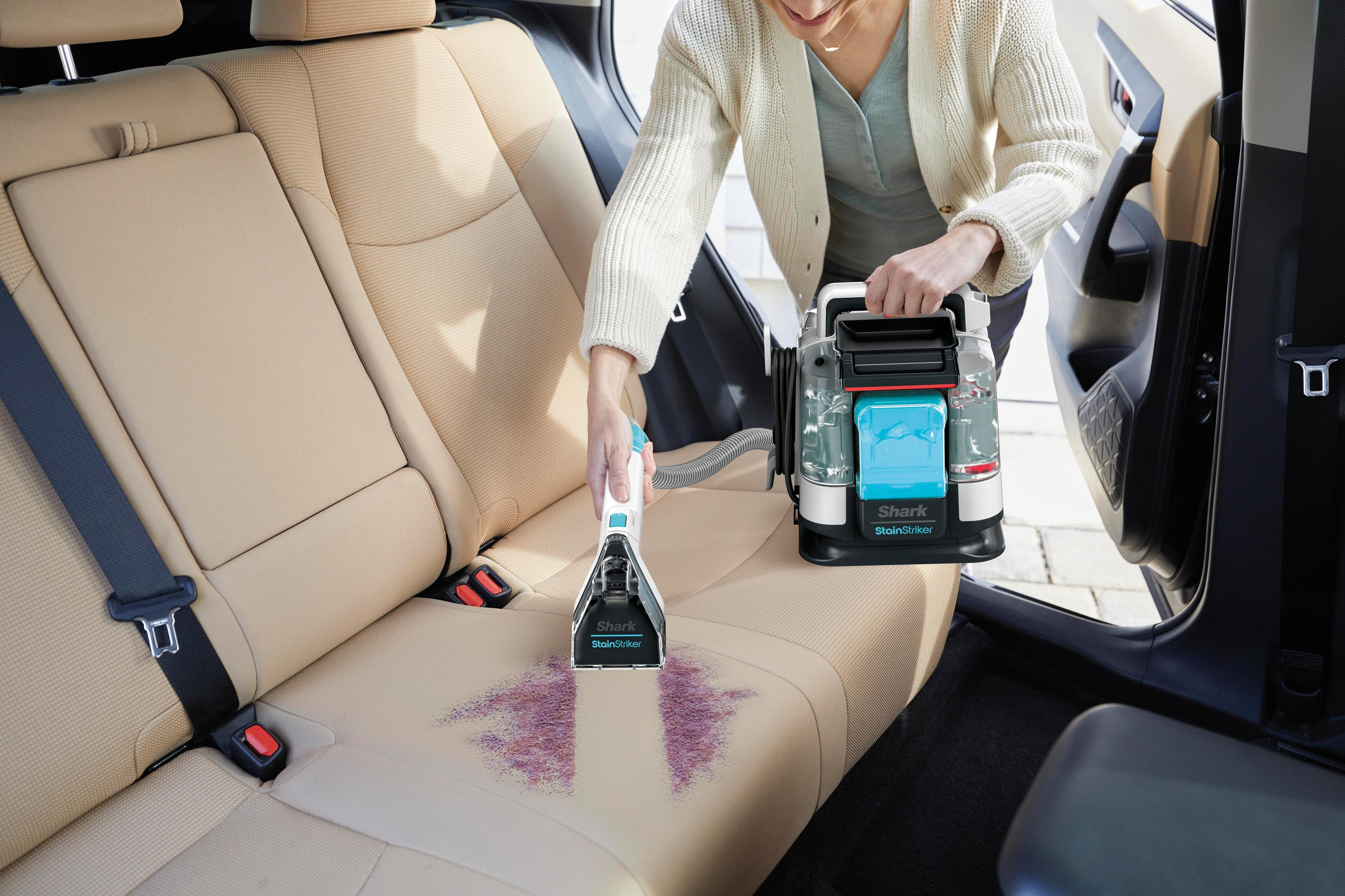 Kobieta czyści siedzenie samochodu odplamiaczem. Siedzenie ma różowe plamy.