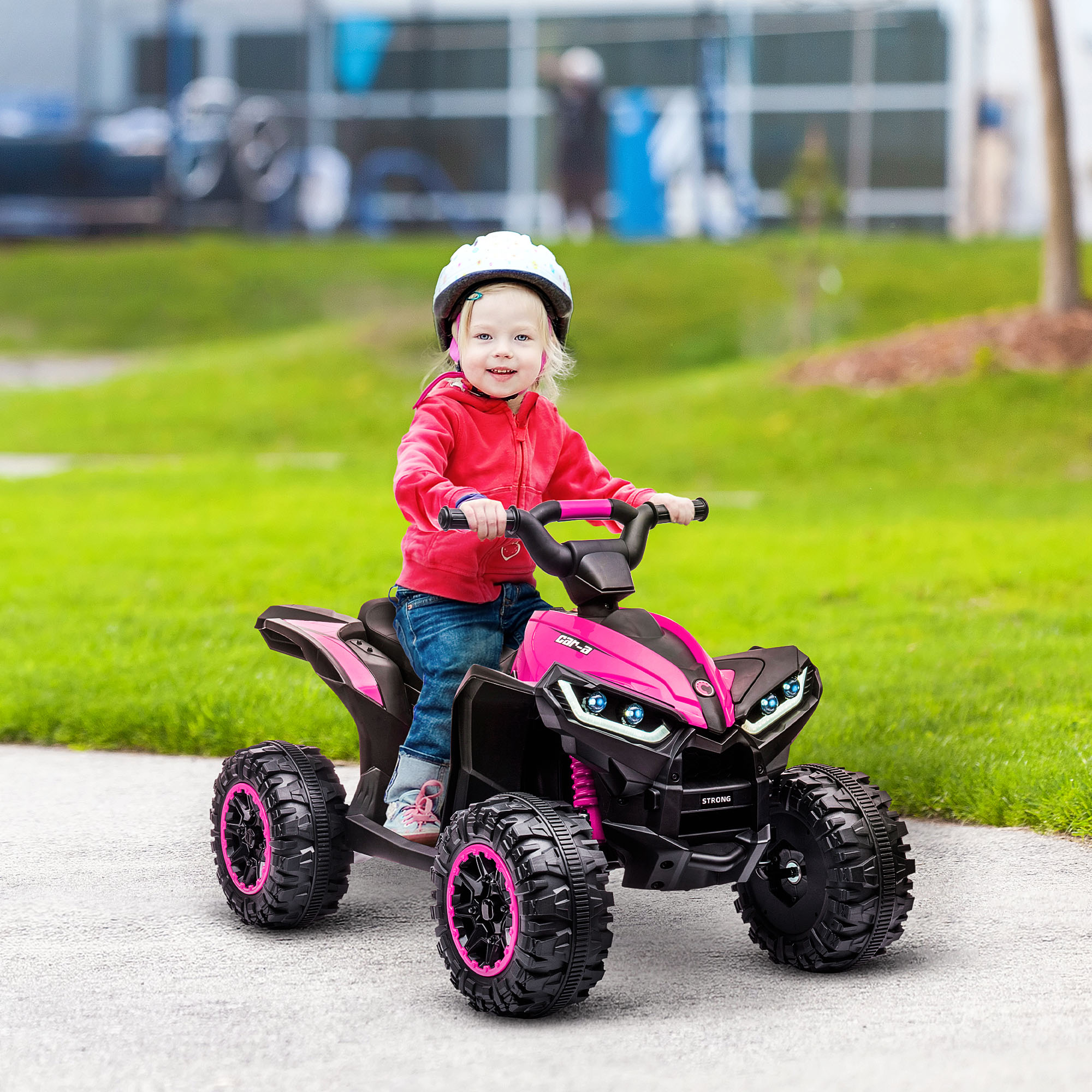 Una niña montando un ATV rosa en un camino pavimentado, sonriendo a la cámara, al aire libre.