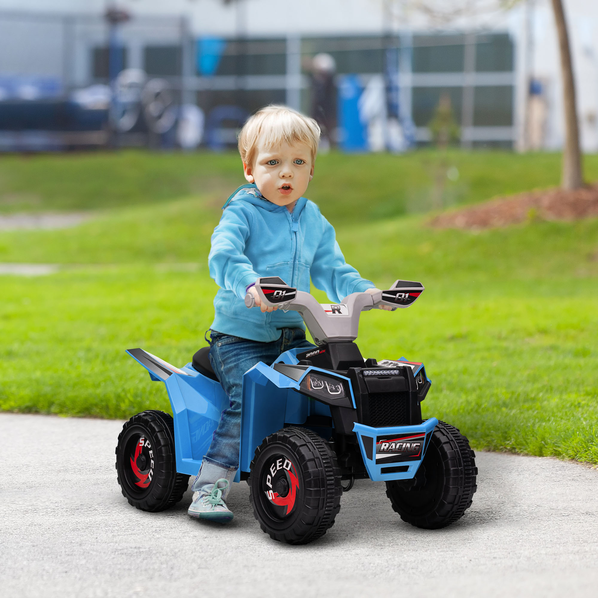 Un bambino piccolo guida un ATV blu su un marciapiede. L'ATV ha pneumatici neri e dettagli rossi.