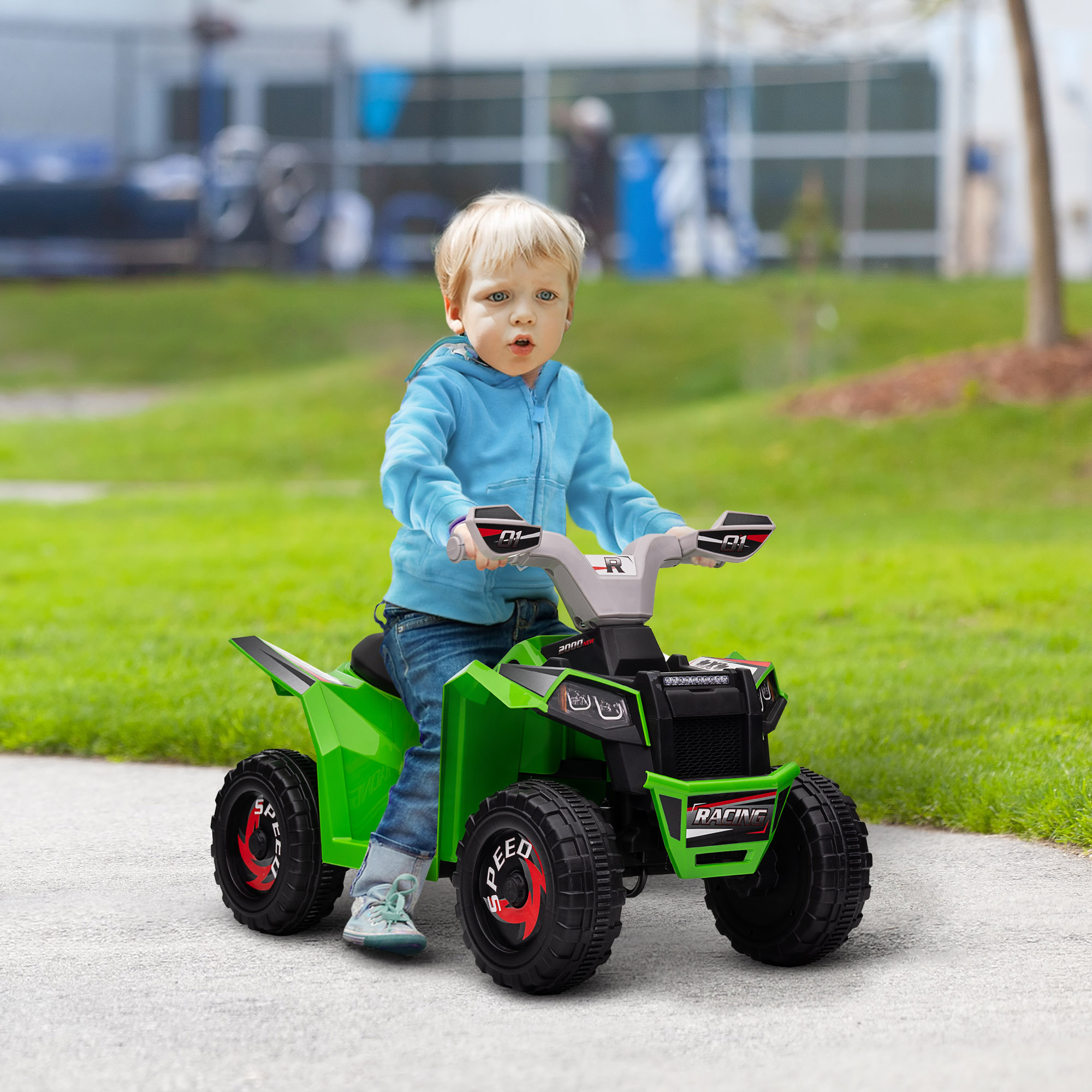 Un niño en un juguete ATV verde, montando en un camino pavimentado.