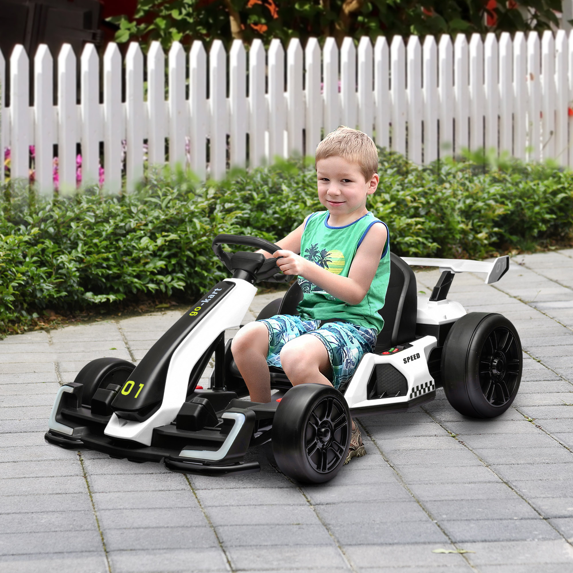 Un bambino è seduto su un go-kart bianco e nero su una superficie pavimentata.
