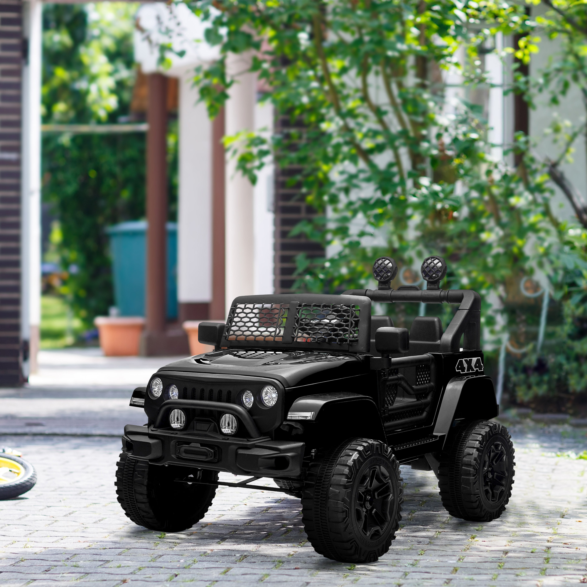 Giocattolo nero stile Jeep con 4x4 sul lato. Ha una griglia anteriore e fari. Ambientato in un giardino.