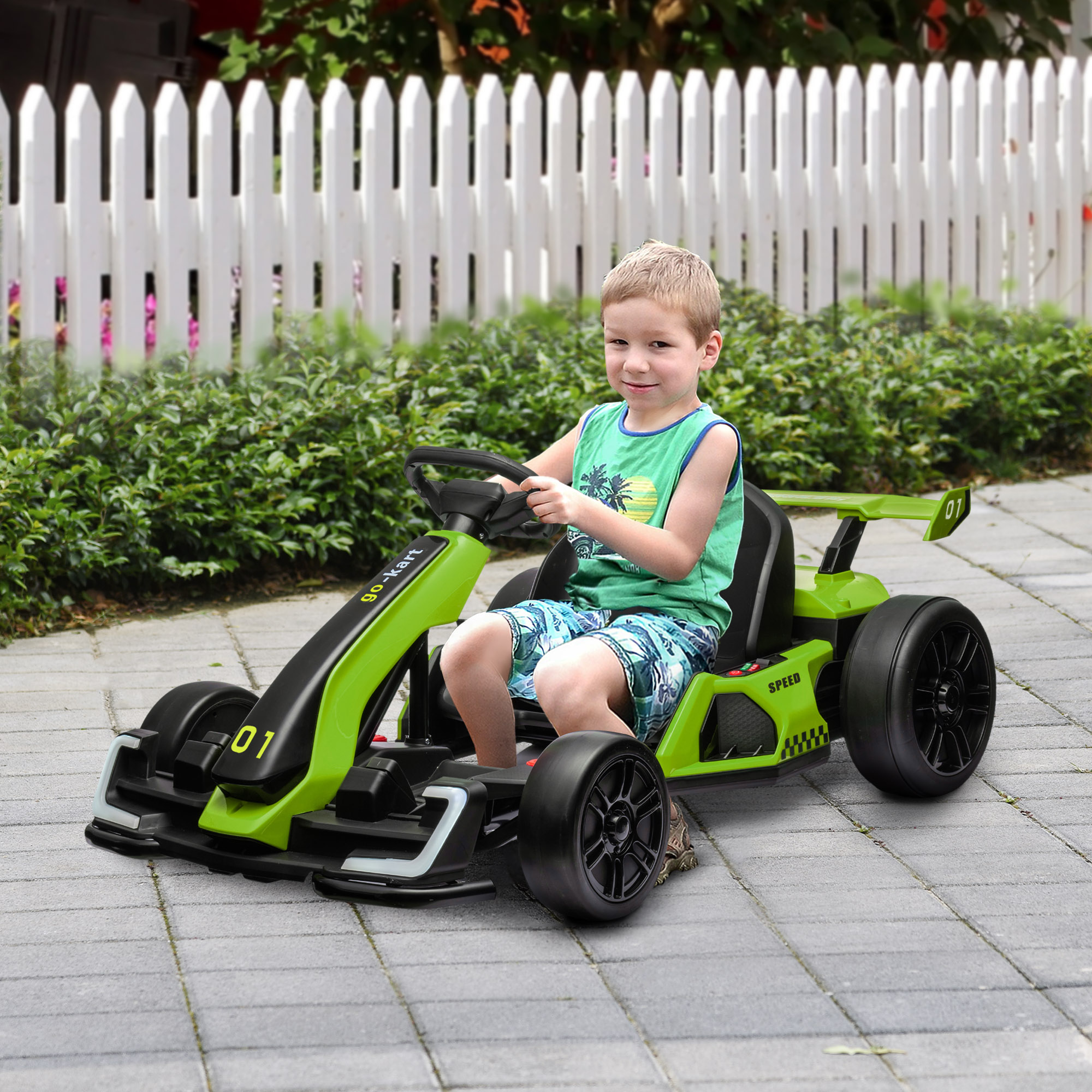 Ragazzino guida un go-kart giocattolo verde su una superficie pavimentata.