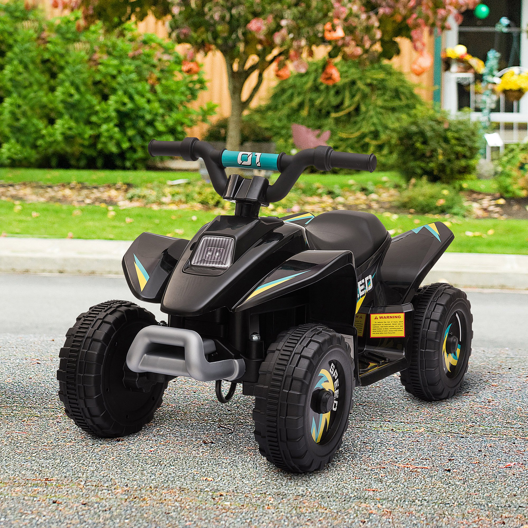 Giocattolo ATV nero con accenti blu. È parcheggiato su una superficie strutturata, con un prato verde e alberi sullo sfondo.