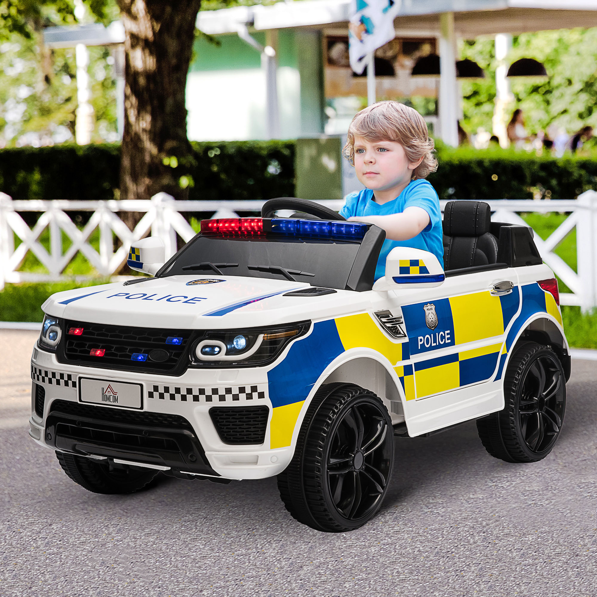 Un bambino guida un'auto della polizia giocattolo su una strada. L'auto è bianca, blu e gialla.