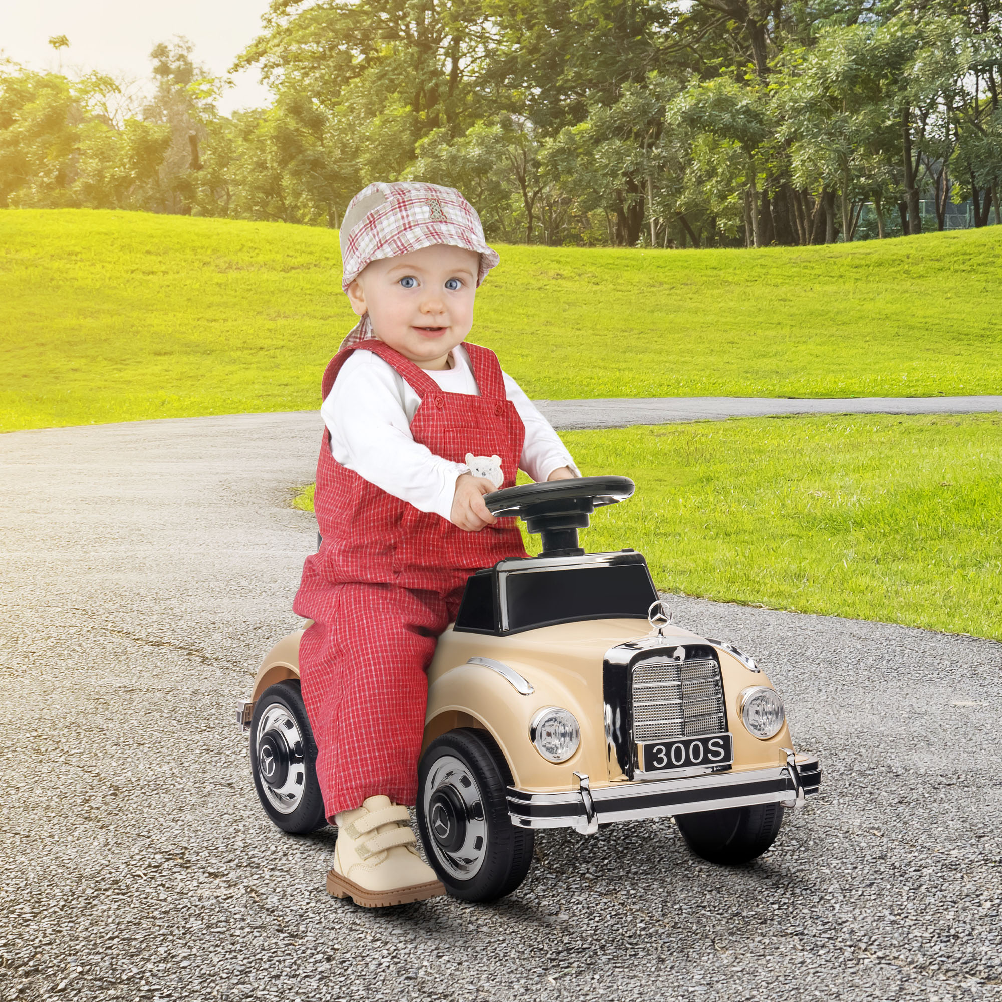 Un bambino è seduto in un'auto giocattolo beige. L'auto ha un logo 300S e lo sfondo è un campo verde.