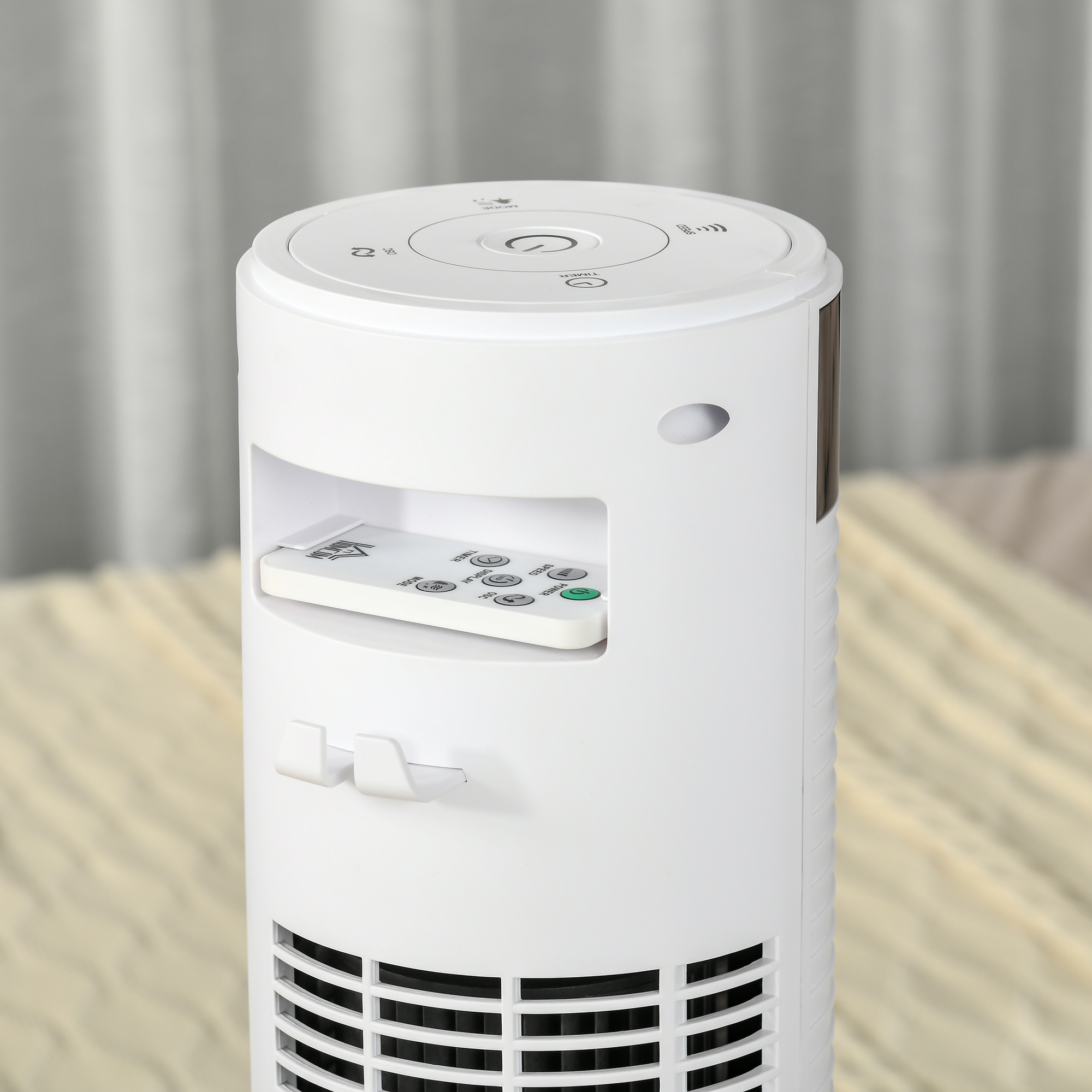 Un ventilatore bianco con telecomando. Ha una forma alta e cilindrica e un pannello di controllo.