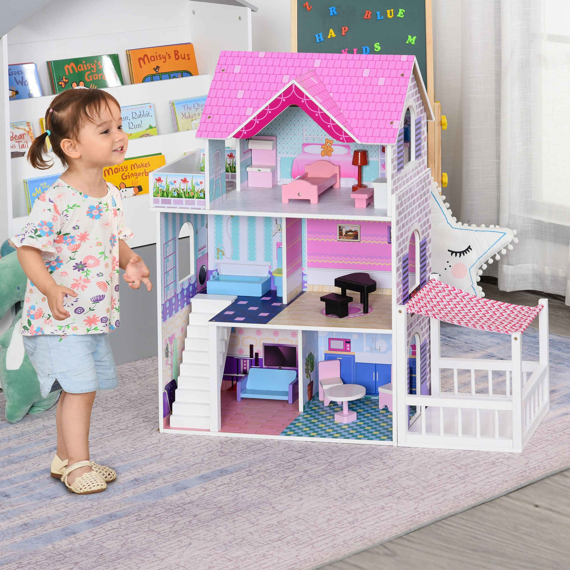 Una bambina è in piedi vicino a una casa delle bambole colorata, piena di mobili.