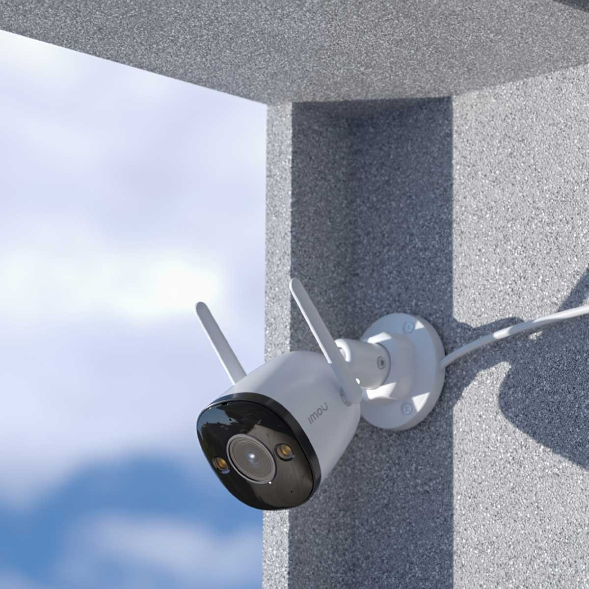Biało-czarna kamera bezpieczeństwa jest zamontowana na szarej ścianie, z błękitnym niebem.