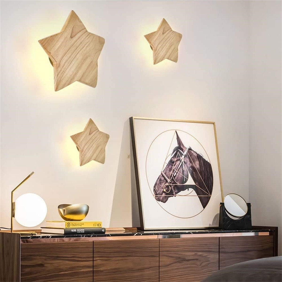 Drei Wandleuchten in Sternform aus Holz und ein Bild eines Pferdekopfes. Eine Lampe und Deko auf einem Holzschrank.