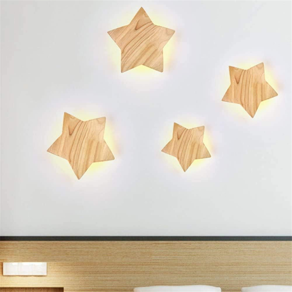 Wandleuchten in Form von Holzsternen. Vier Sterne mit warmem Schein an weißer Wand.