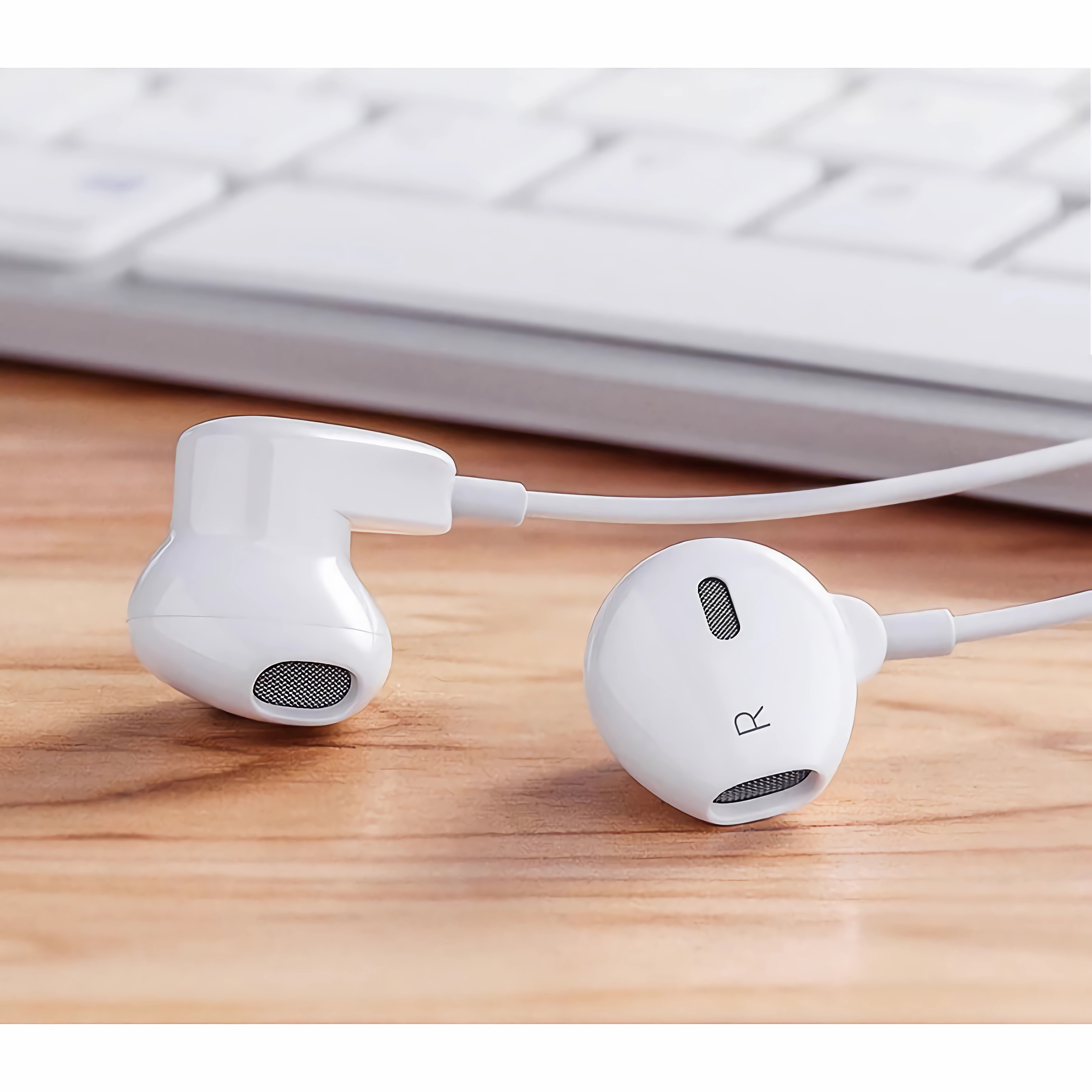 Weiße Ohrhörer: zwei In-Ear-Kopfhörer mit Mesh-Abdeckungen und einem weißen Kabel. Auf Holzoberfläche.