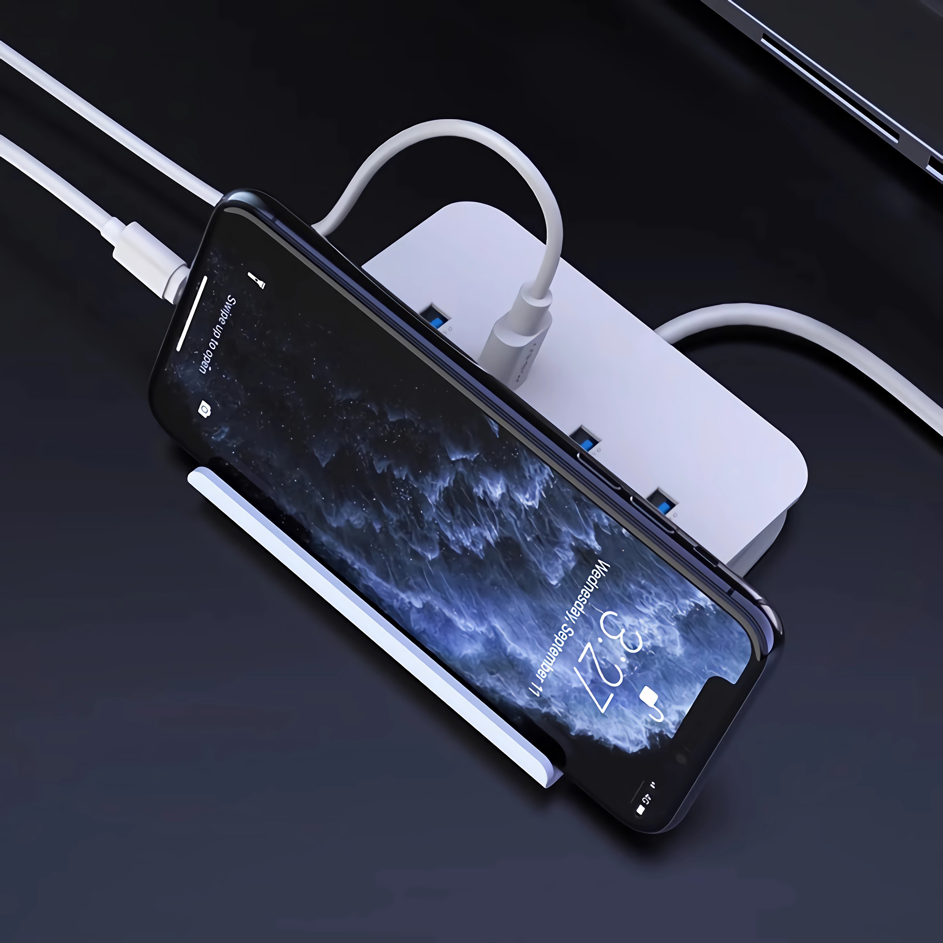 Ein Telefon wird an einem weißen Ladehub aufgeladen. Das Telefon ist schwarz und hat einen Bildschirm.