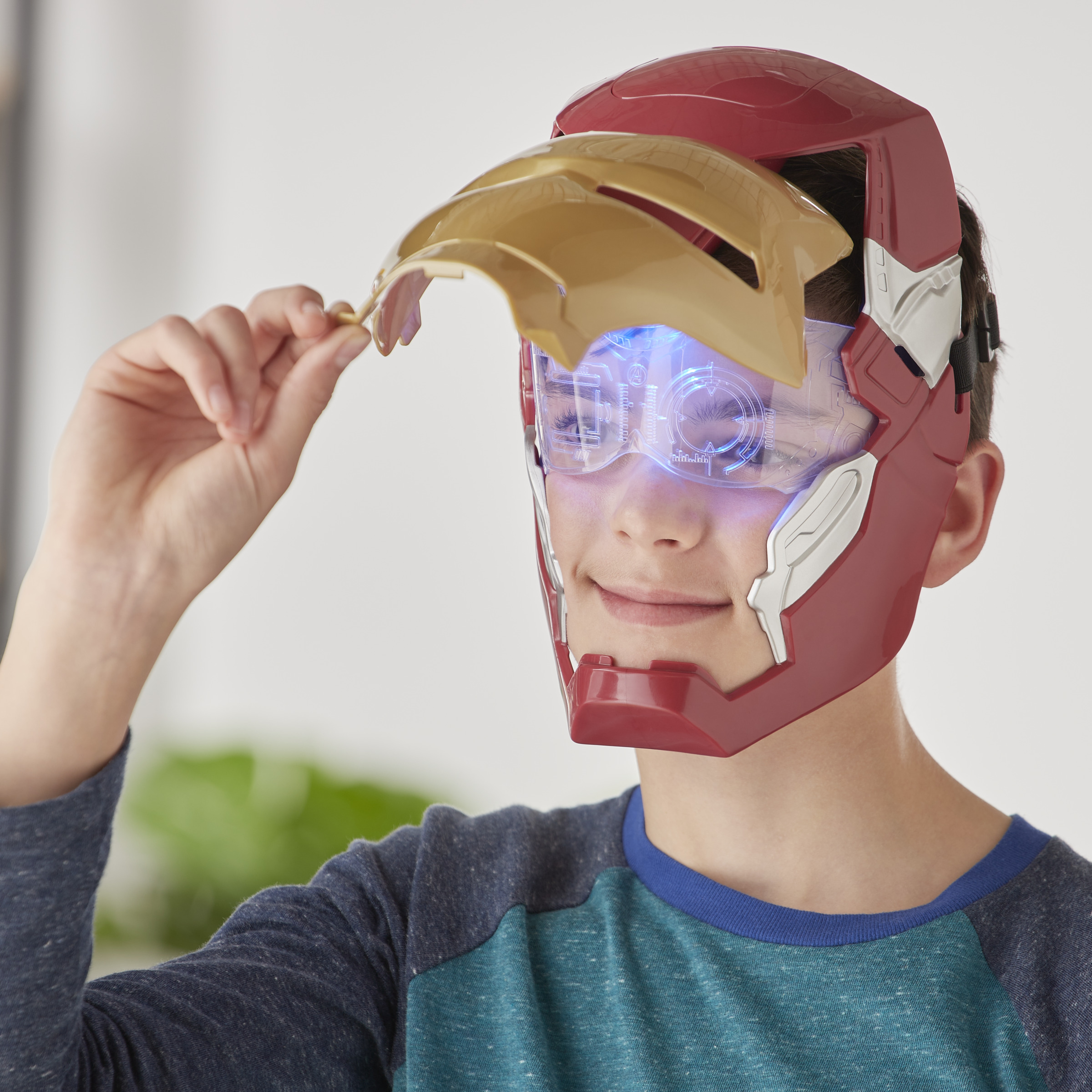 Persona con máscara de Iron Man, sosteniendo la placa frontal con visor azul iluminado.