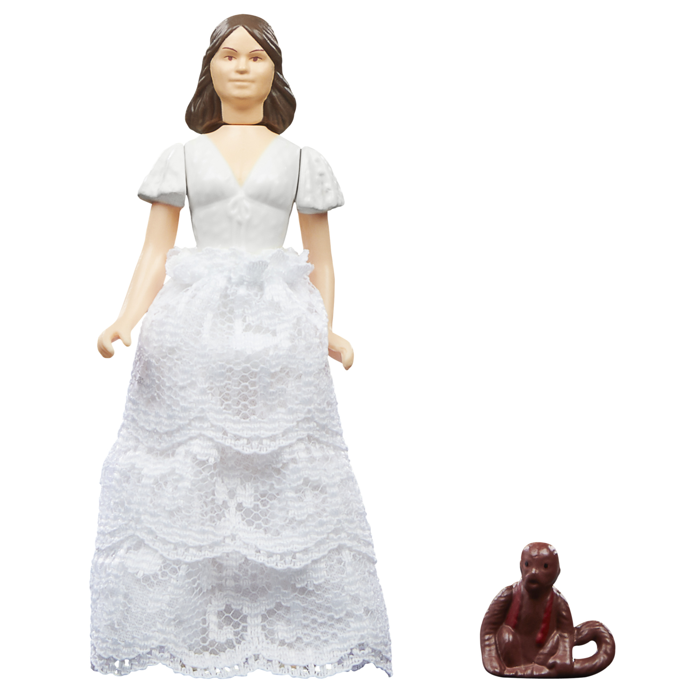 Una mujer con un vestido blanco y una pequeña figura de mono marrón. La mujer mira a la cámara.