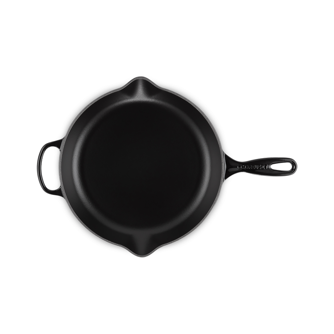 Eine schwarze Gusseisenpfanne, Draufsicht. Die Pfanne hat einen Griff und eine kleine Schlaufe. Der Hintergrund ist weiß.