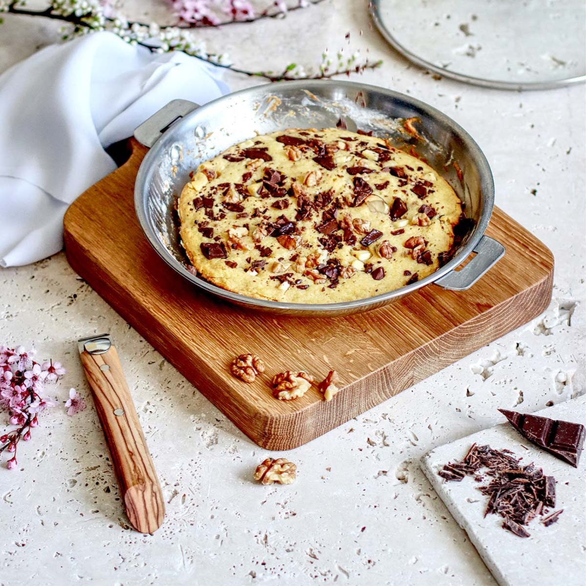 Ciastko w patelni na drewnianej desce z orzechami włoskimi i czekoladą.