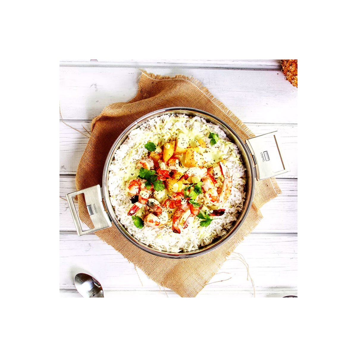 Miseczka ryżu z krewetkami, ananasem i ziołami, na worku jutowym na białym drewnianym stole.