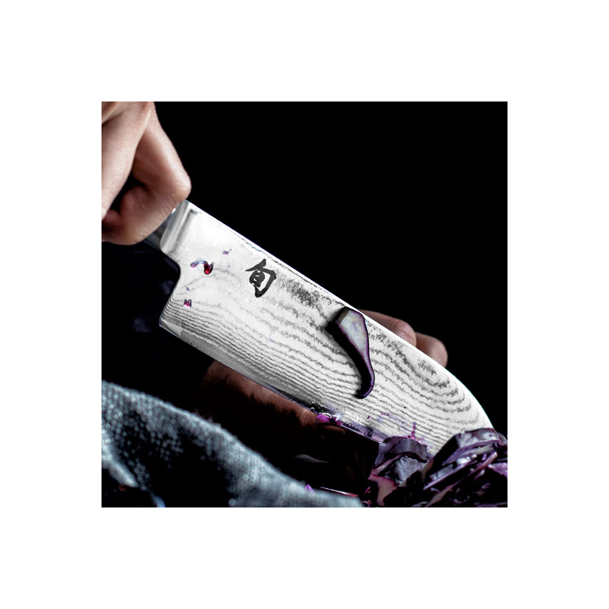Eine Hand, die ein Messer hält und lila Kohl schneidet, mit einem japanischen Zeichen auf der Klinge.