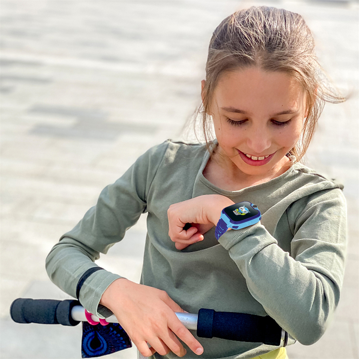 Ein Mädchen betrachtet ihre Smartwatch, hält Rollergriffe. Die Uhr zeigt einen blauen Bildschirm.