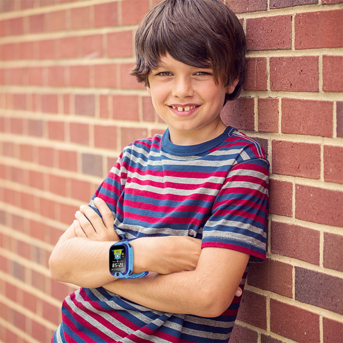 Ein Junge mit einer blauen Smartwatch, der an einer Backsteinmauer steht.