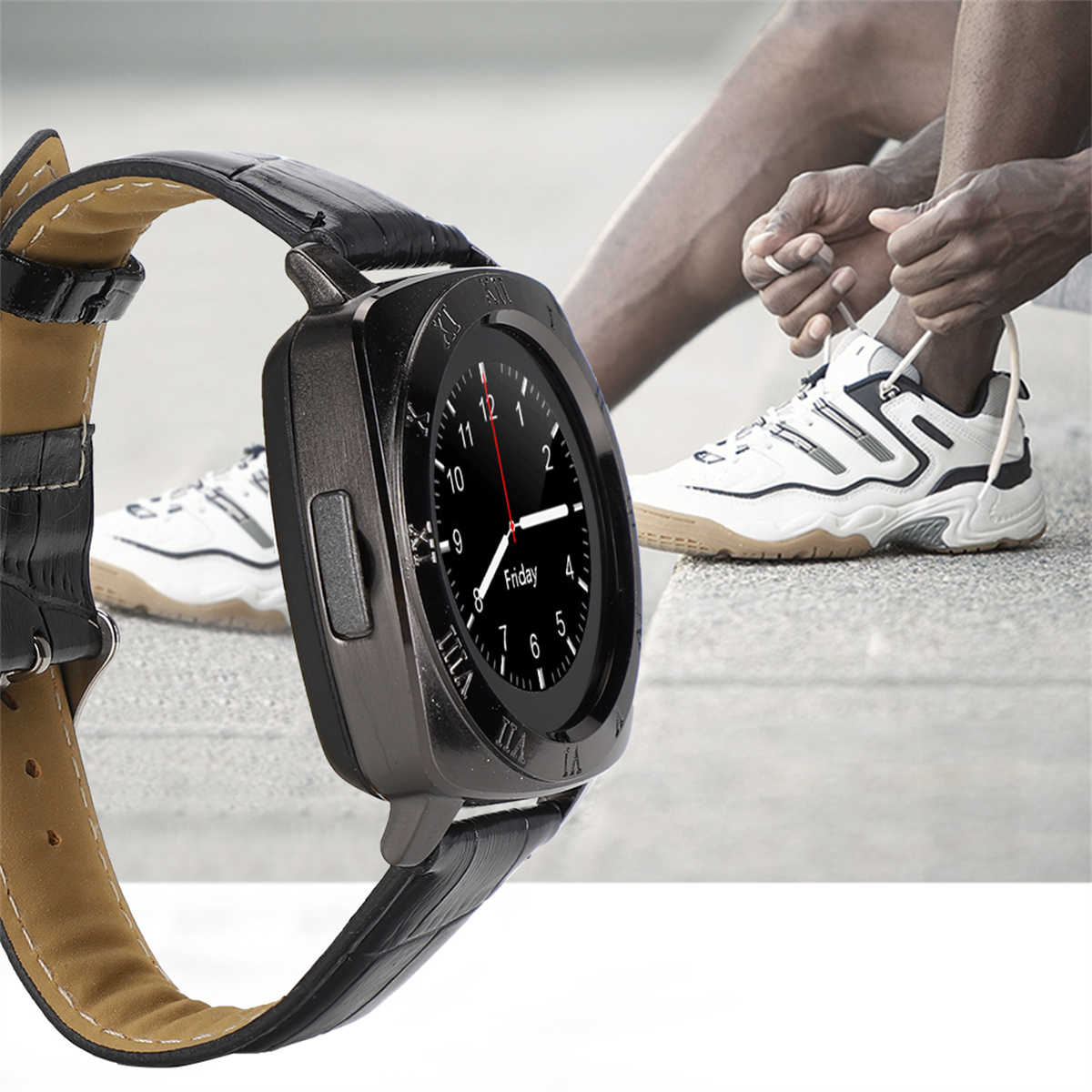 Schwarze Smartwatch mit Lederarmband. Person bindet Schnürsenkel im Hintergrund.