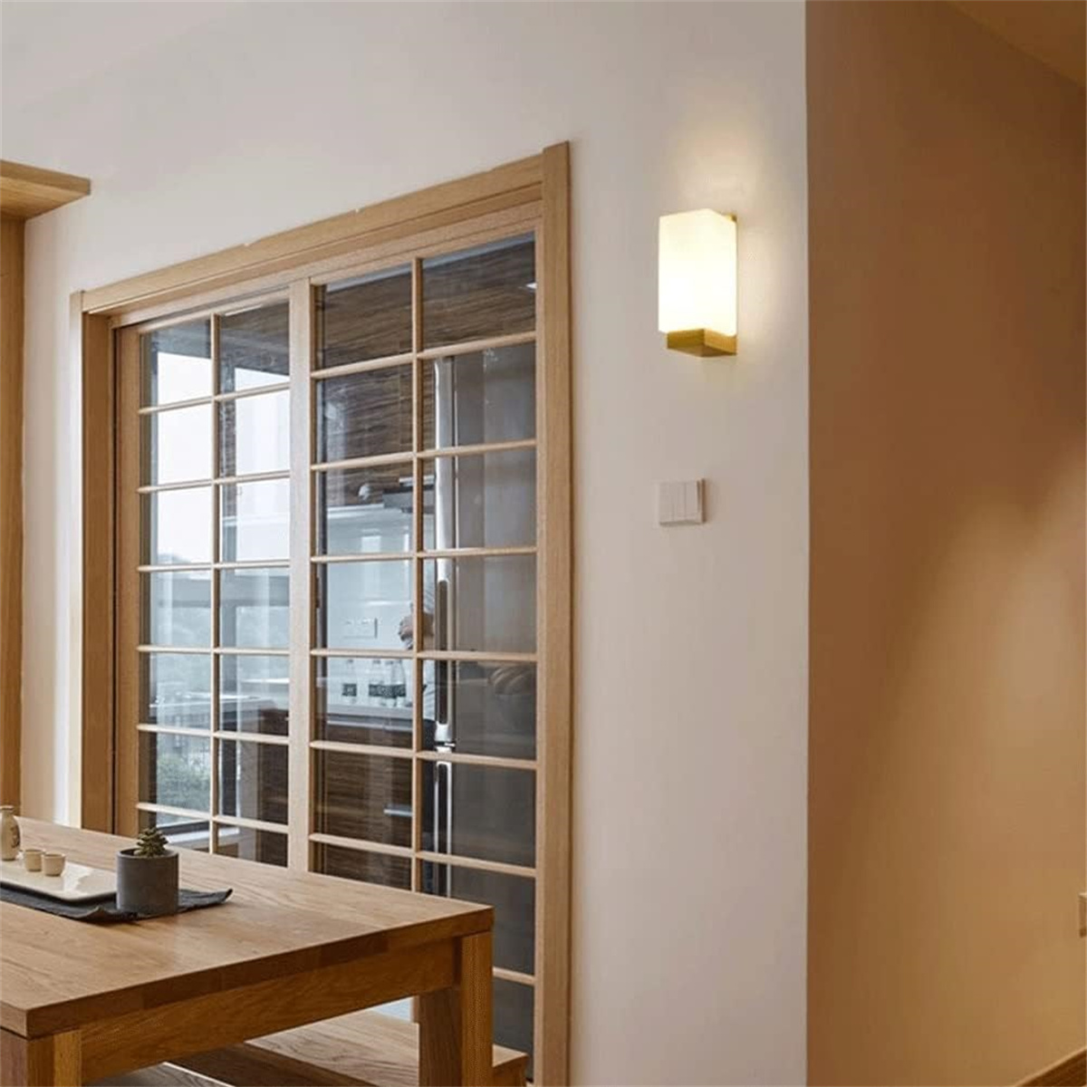 Holztisch, Schiebetür aus Glas und Wandleuchte. Innenaufnahme.