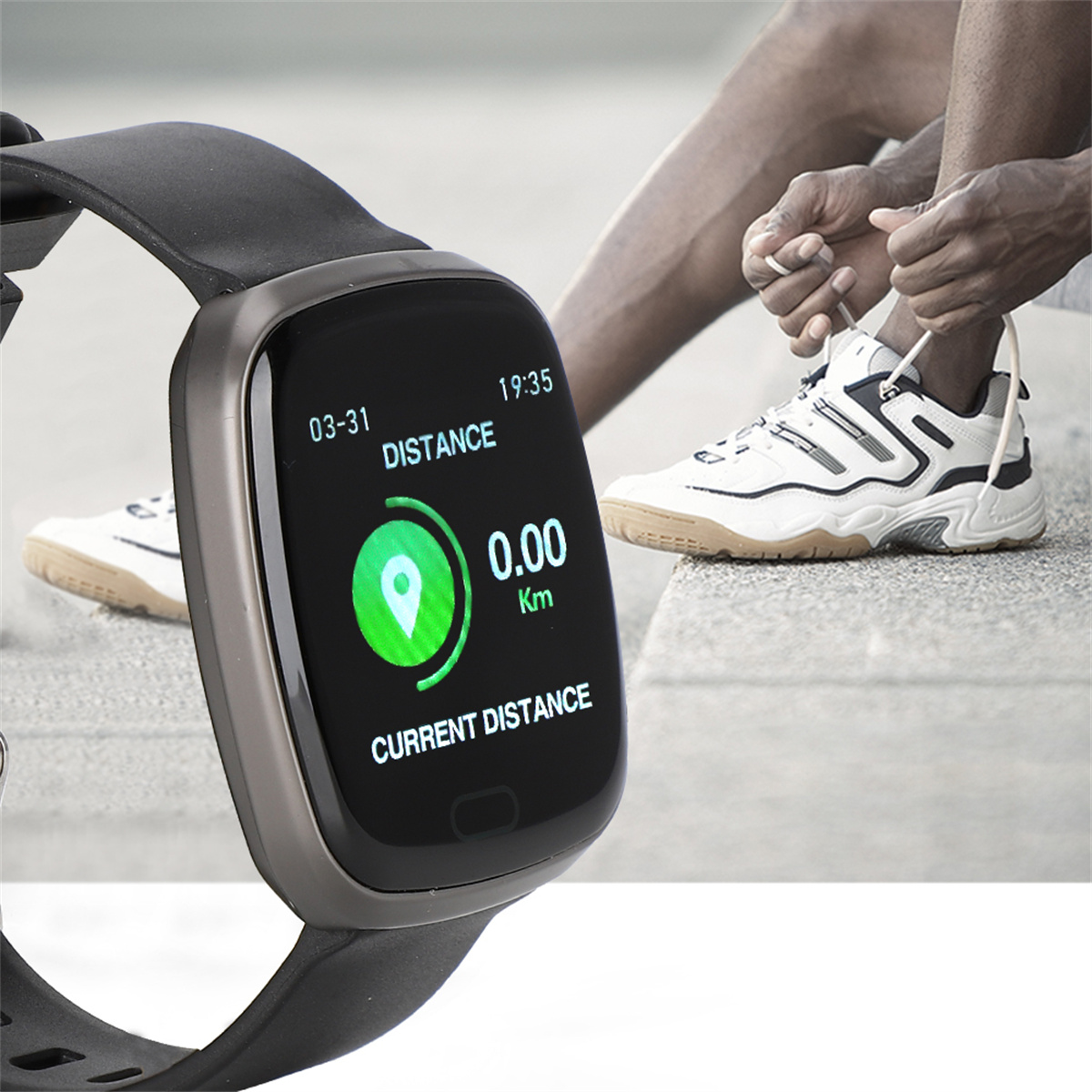 Eine Smartwatch zeigt '0,00 km' und ein Standortsymbol an. Eine Person bindet sich im Hintergrund die Schuhe.