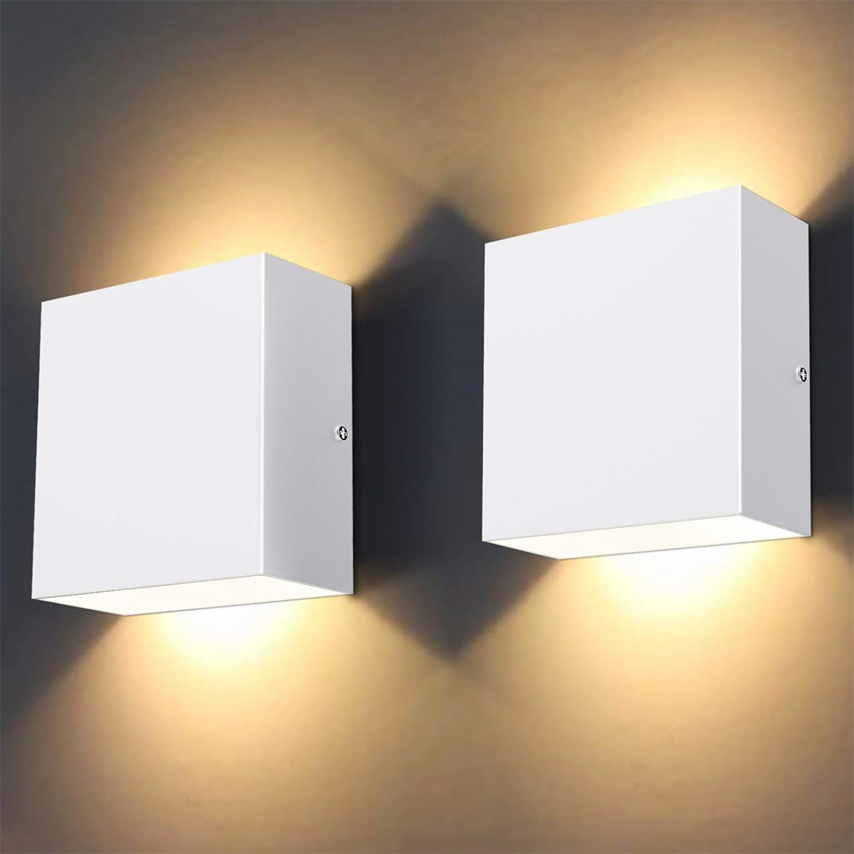 Zwei weiße, quadratische Wandleuchten leuchten und werfen Schatten auf eine graue Wand. Die Lichter sind an.