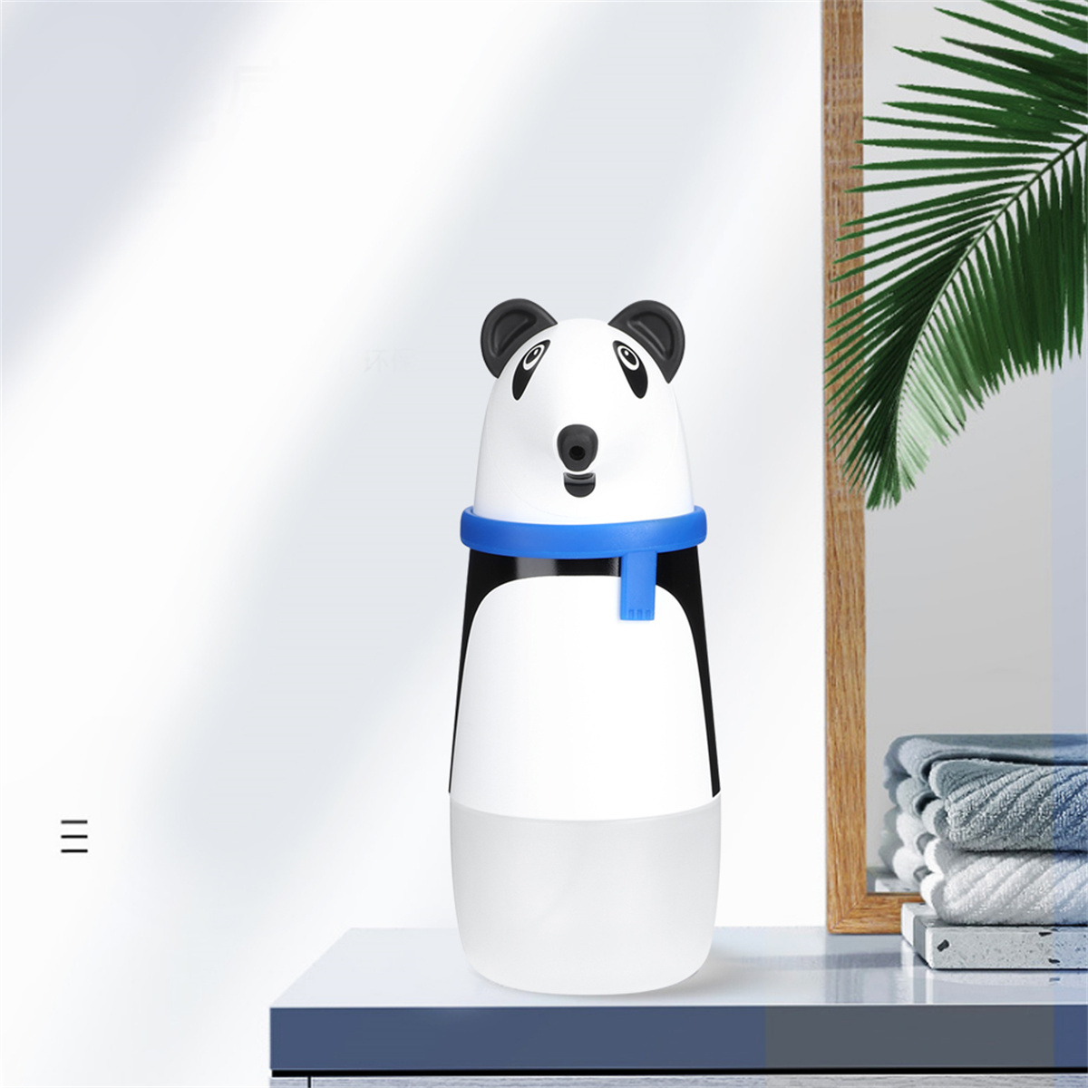 Seifenspender in Panda-Form in einem Badezimmer. Er ist weiß und schwarz mit blauem Kragen.