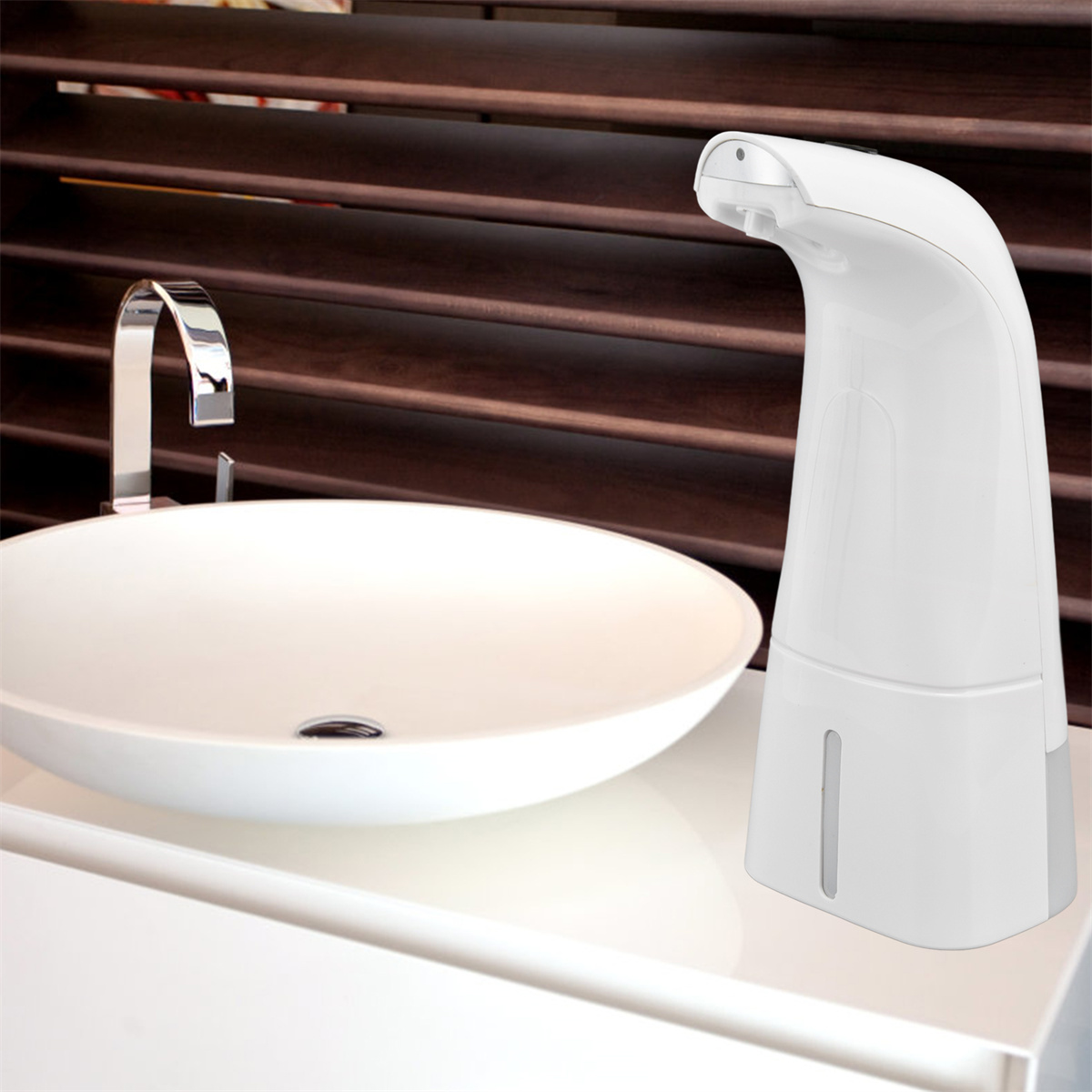 Weißer, automatischer Seifenspender auf weißer Theke neben einem Waschbecken.