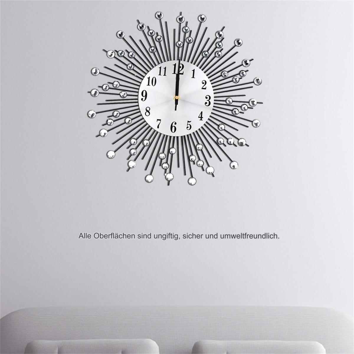 Eine Sonnenstrahl-Wanduhr mit Kristallakzenten an einer weißen Wand. Die Uhr hat schwarze Zeiger.
