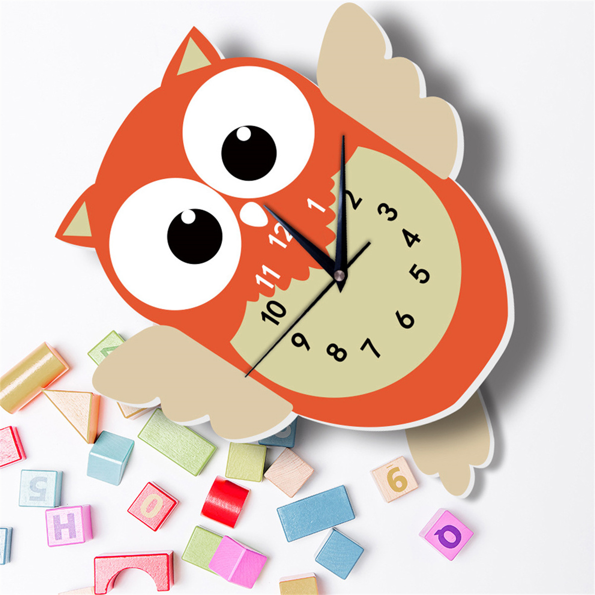 Eulen-förmige Uhr mit bunten Blöcken drumherum auf weißer Oberfläche.