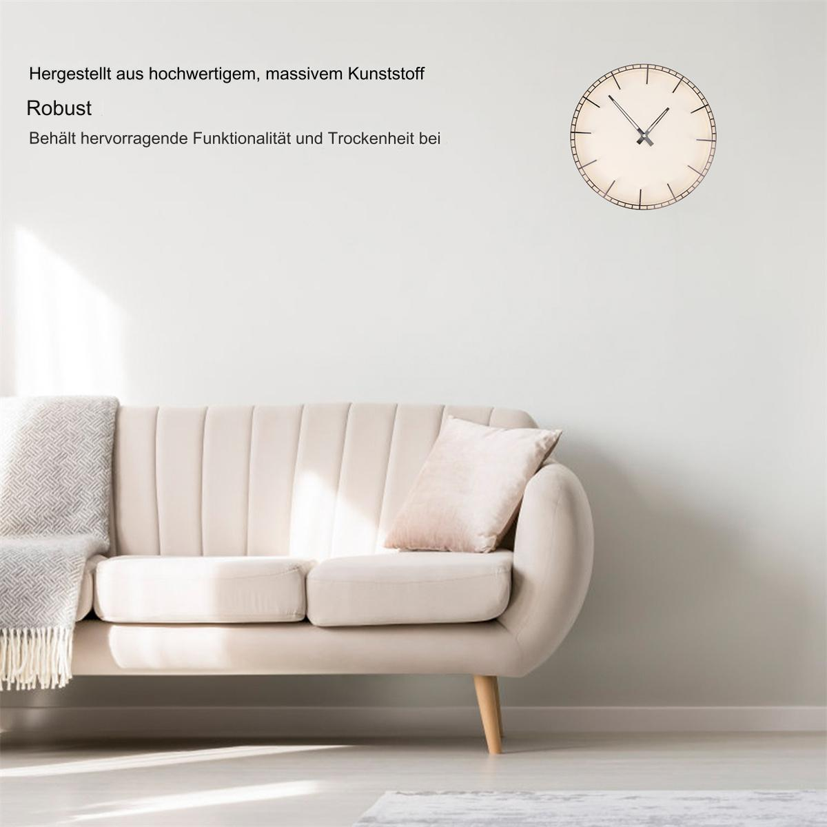 Beiges Sofa mit Decke und Kissen vor weißer Wand. Eine Uhr hängt an der Wand.