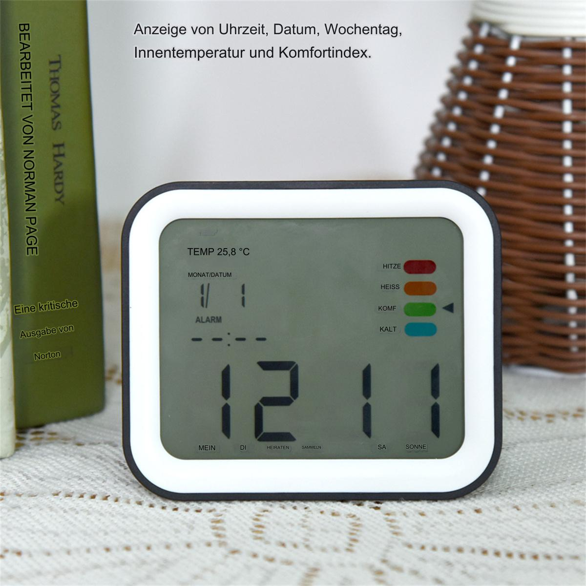 Digitaler Wecker mit Anzeige von Zeit, Datum und Temperatur. Bücher und Korb im Hintergrund.