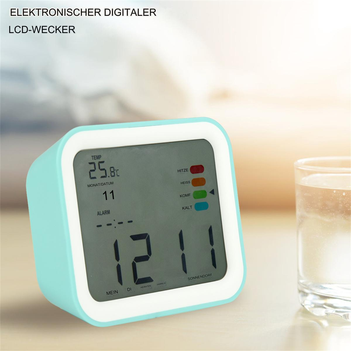 Digitaler Wecker, türkisfarbener Rahmen, schwarzes Display. Zeigt Zeit, Datum und Temperatur.